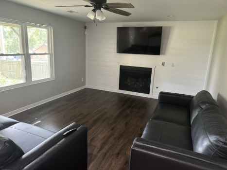 Rebuilt living room with shiplap accent wall and fireplace after Restor KC water damage repair